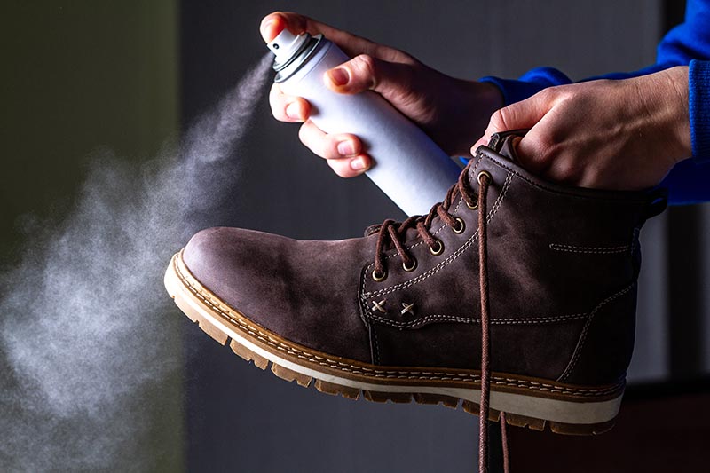 A person is cleaning and spraying agent on men's suede casual boots