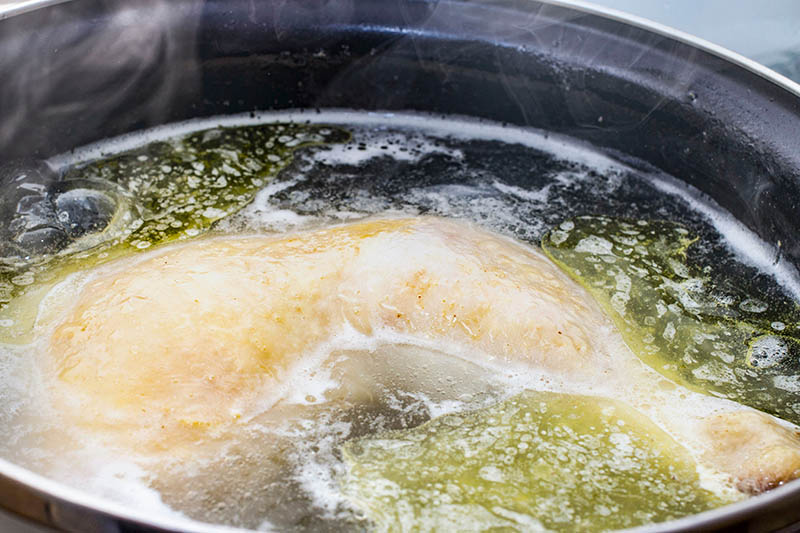 boiled chicken in a pot broth close-up with blurred