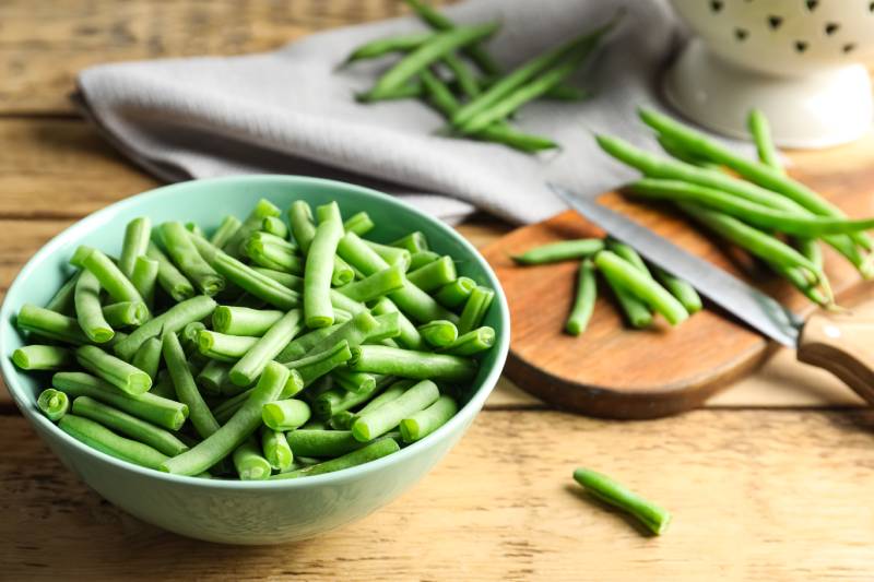 Fresh green beans in bowl on wooden table