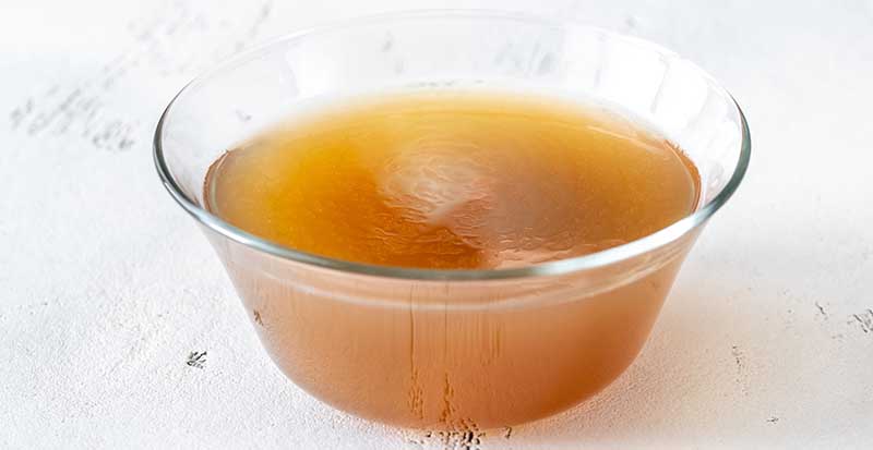 Glass bowl of beef bone broth on white table