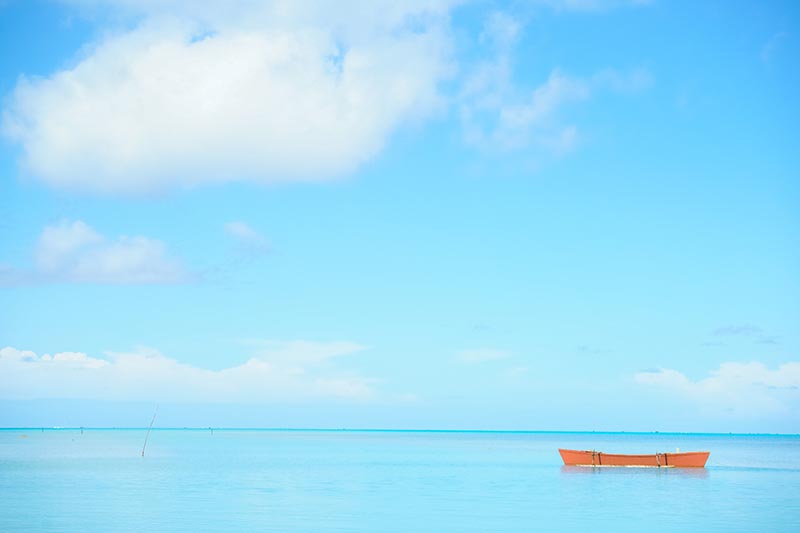Orange color outrigger canoe on turquoise tropical water view
