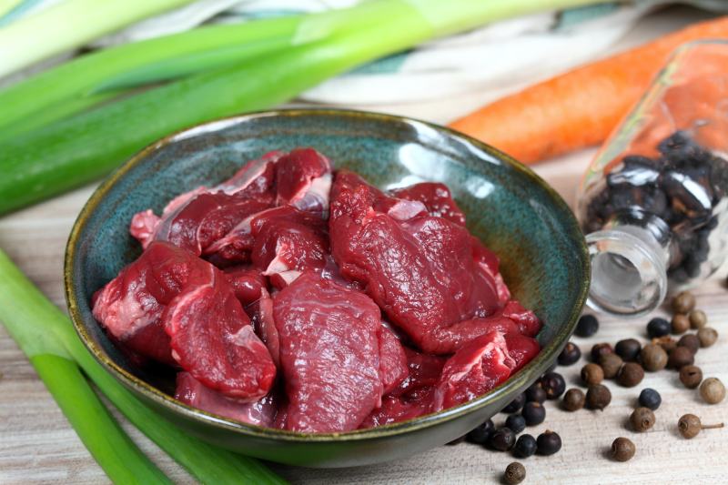 Raw deer meat for venison ragout or goulash on the plate with spices
