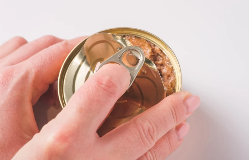 close up of person's hands opening a can of wet pet food