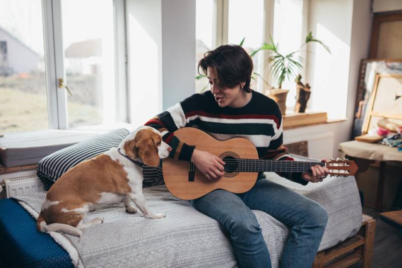 man playing guitar with his dog at home