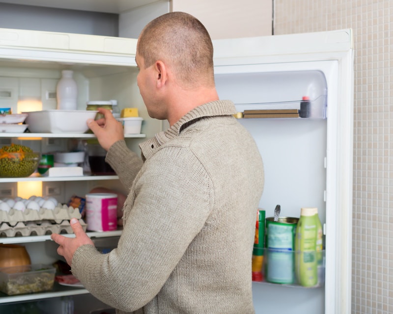 man putting food in the fridge