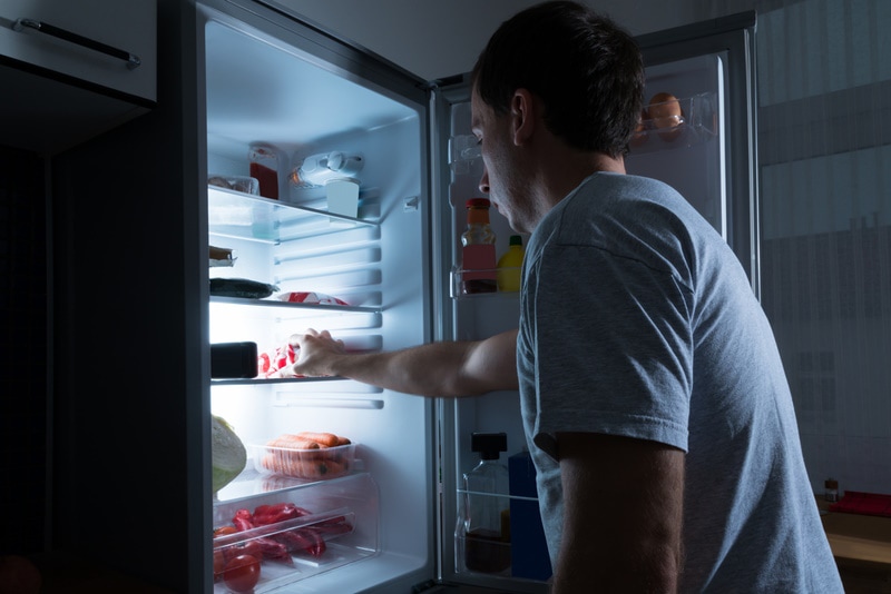 man storing food in fridge