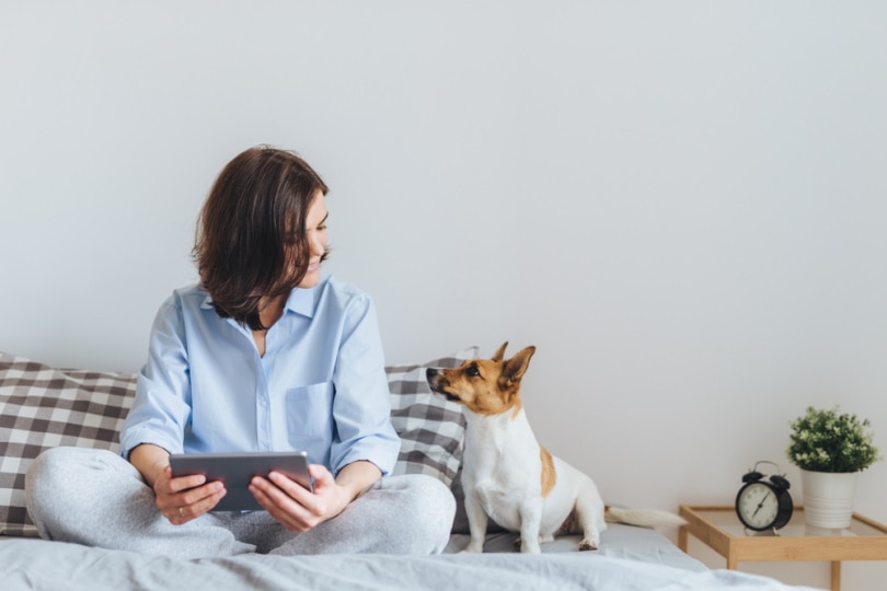 owner and her dog sits on bed