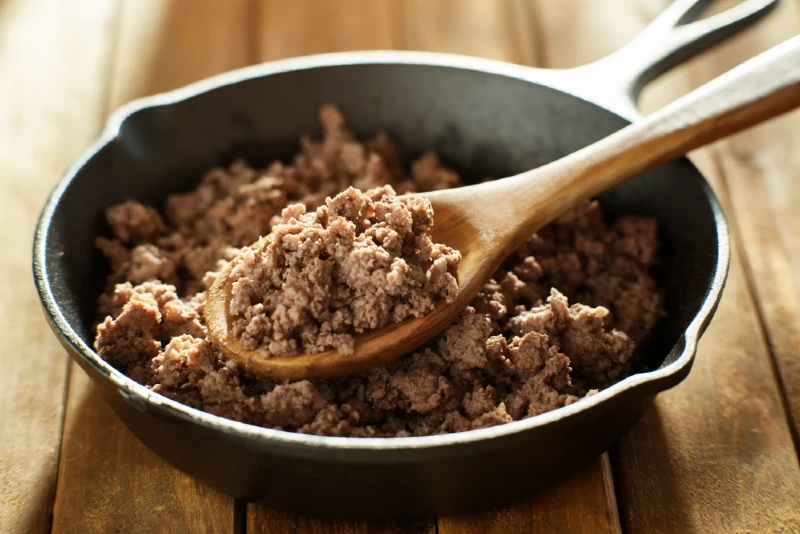 spoonful of freshly cooked ground beef in iron skillet