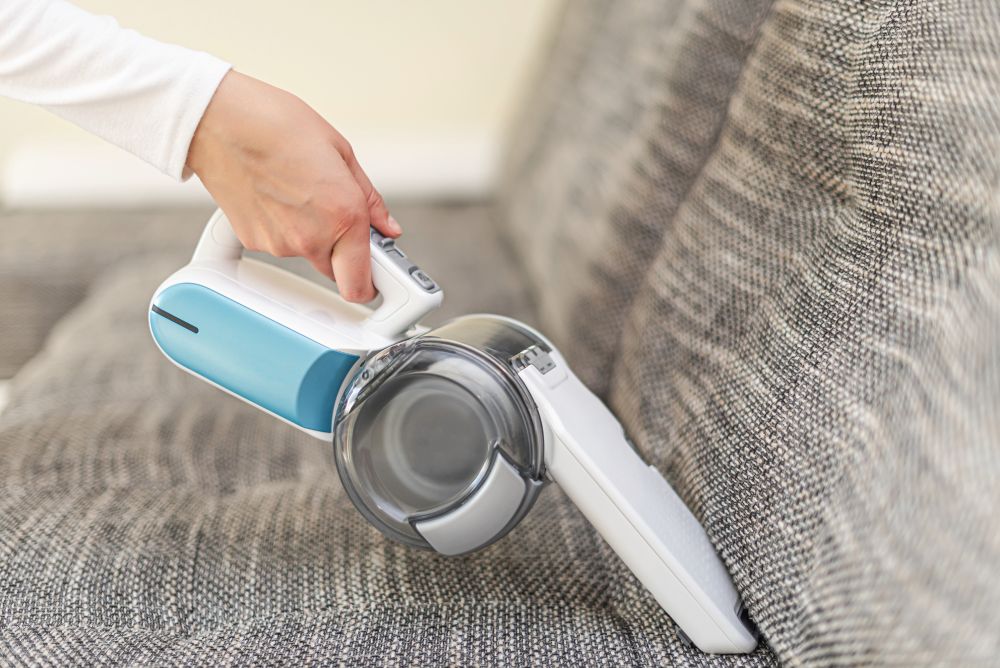 vacuuming furniture in a house with a hand-held portable vacuum cleaner