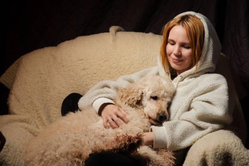woman lies with a large dog on the couch