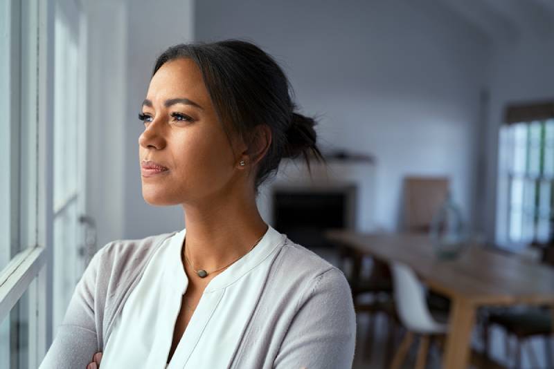 woman looking outside window with uncertainty