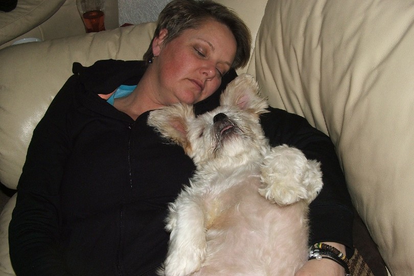 woman sleeping with her dog on the couch