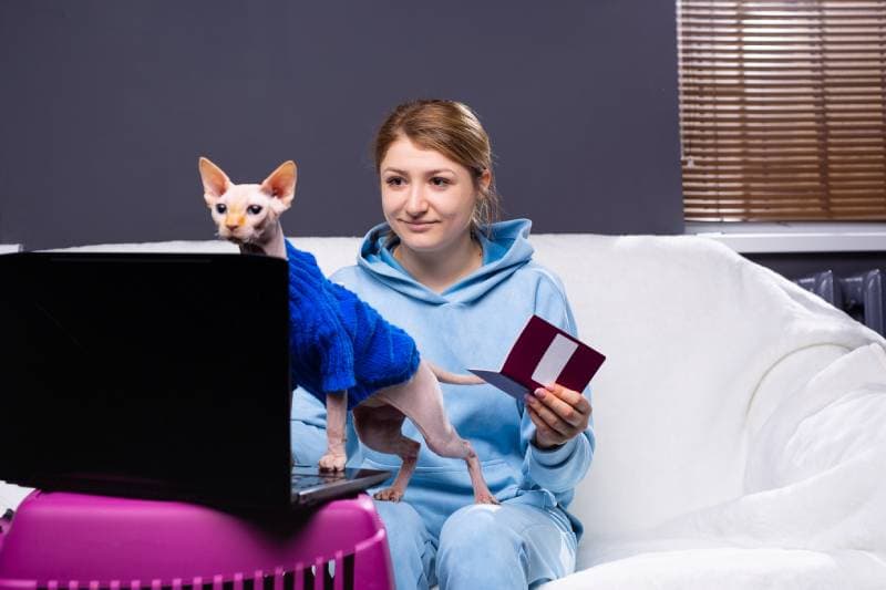woman with pet passport in front of laptop