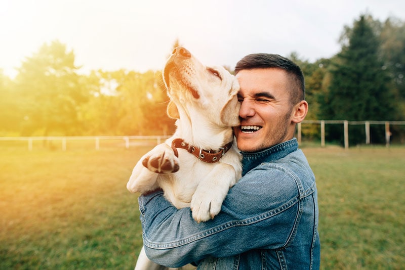 young man holding labrador dog