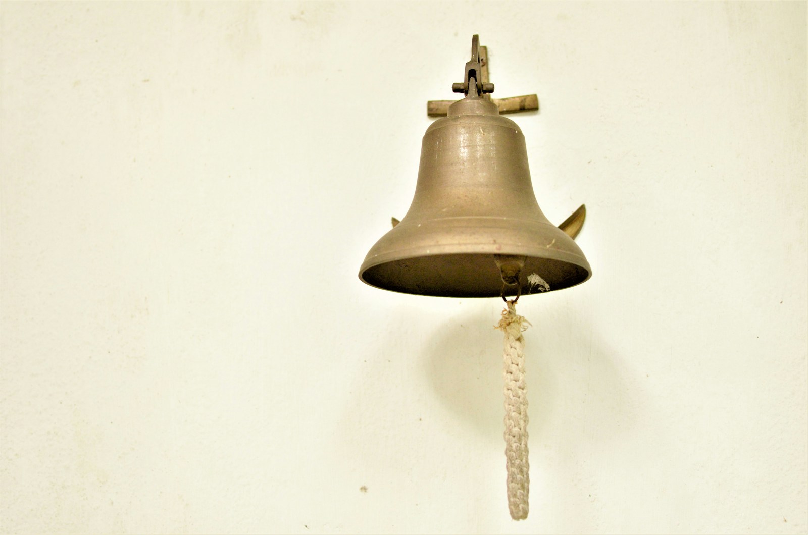 a bell hanging on a wall with a rope
