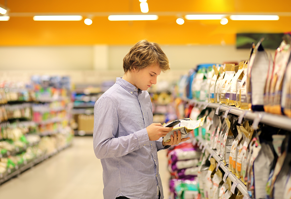 young man shopping reading Pet food label