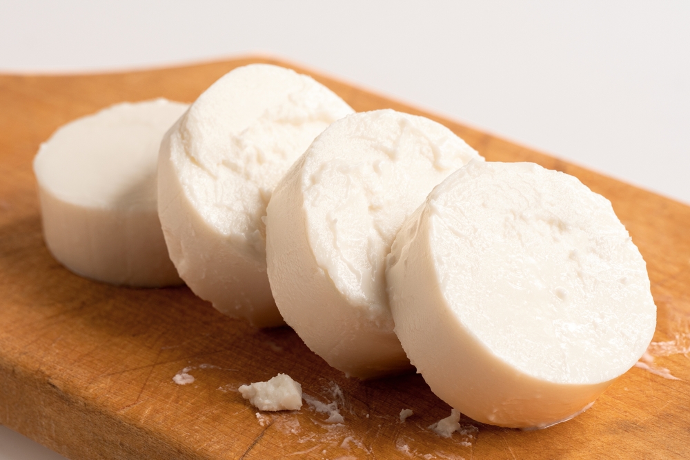 Rounds of goat cheese on wood chopping board